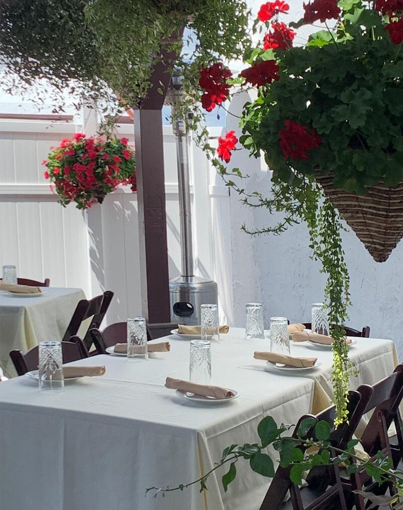 Second floor veranda with table set up and colorful baskets of flowers