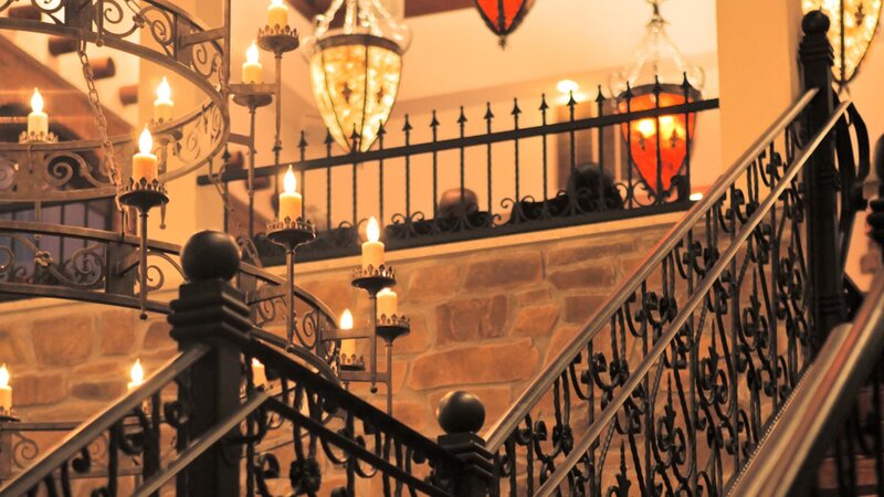 View of iron staircase and chandelier ascending to the second floor dining room