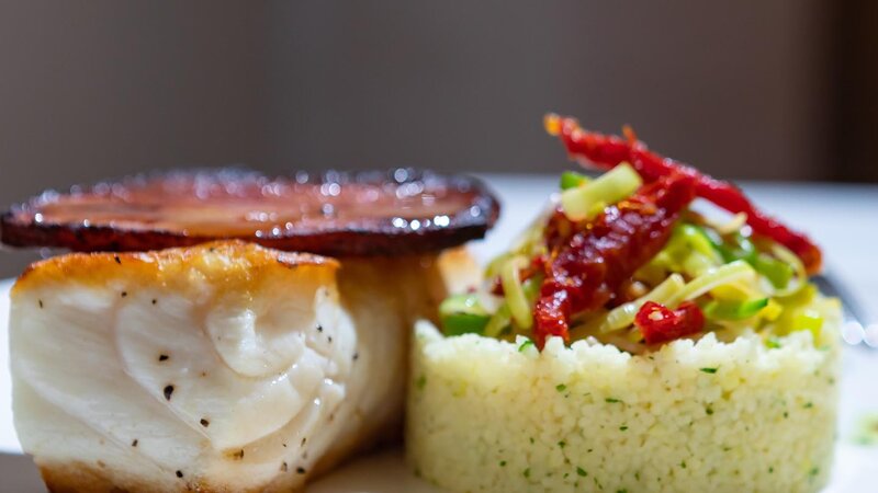 Pan seared halibut topped with apple wood bacon accompanied with couscous and julienned vegetables